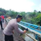 Anggota Polres Musi Rawas melakukan kegiatan ngecat Jembatan Merah Putih Sungai Kungku di Desa Purwodadi, Kecamatan Jayaloka, Kabupaten Musi Rawas